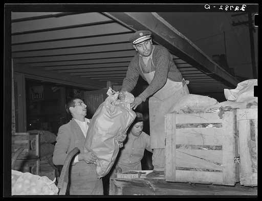 Loading bananas onto a truck at early morning vegetable market. San Antonio, Texas