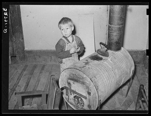 Child of relief family standing by stove made of oil drum. Near Jefferson, Texas