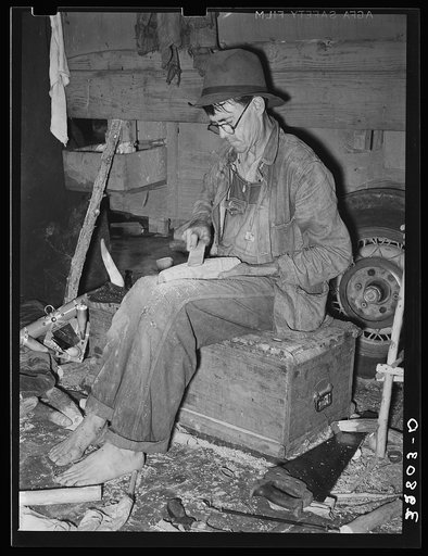 Migrant worker who makes ornaments from horns. He is filing down a wooden block to be used as base for horns. Near Hammond, Louisiana