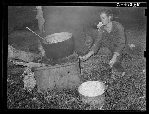 Migratory berry picker putting trash into fire. Near Ponchatoula, Louisiana