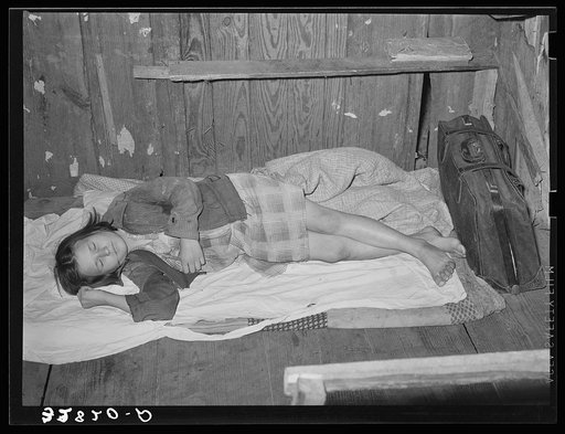 Daughter of migratory berry picker taking a nap on her bed on the floor.  Near Ponchatoula, Louisiana