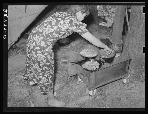 White migratory berry picker preparing dinner in front of tent near Hammond, Louisiana