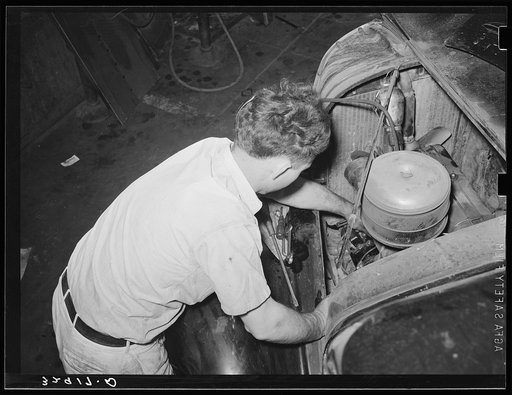 Mechanic working on motor of automobile in garage. San Augustine, Texas