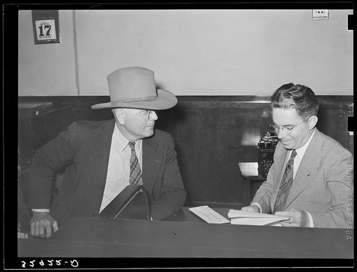 Sheriff of adjoining county talking to cashier in bank. San Augustine, Texas