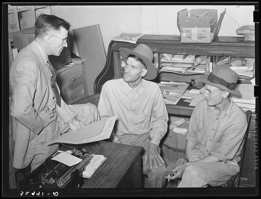 Assistant county agent talking to farmers in his office. San Augustine, Texas
