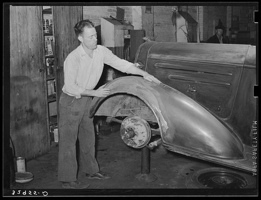 Refinishing fender on automobile in garage. San Augustine, Texas