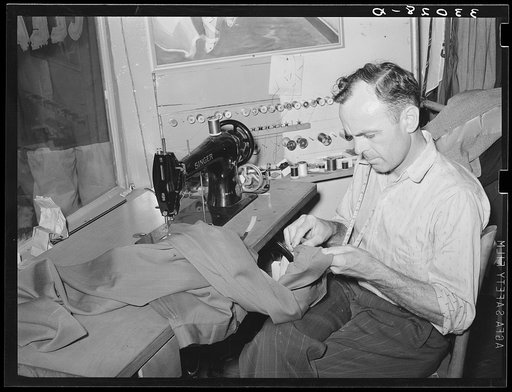 Tailor shortening a pair of trousers. San Augustine, Texas