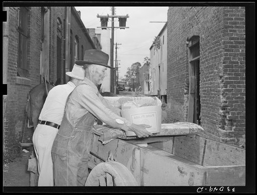 Farmer loading wagon in alley. San Augustine, Texas