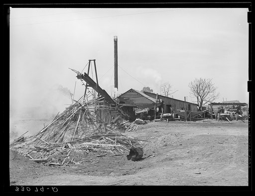 Untitled photo, possibly related to: Sawmill and waste lumber pile being burned. Wells, Texas
