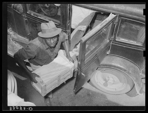 Negro unloading crate of strawberries at loading point. Hammond, Louisiana