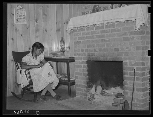Wife of FSA (Farm Security Administration) client sewing in front of fireplace in her home on Sabine Farms. Marshall, Texas