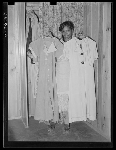 Wife of FSA (Farm Security Administration) client holding dresses which she made from flour sacks. Sabine Farms, Marshall, Texas