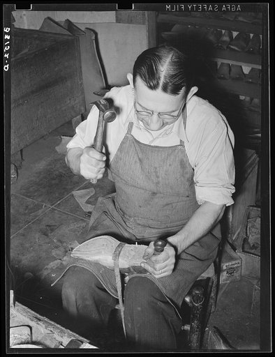 Bootmaker pounding wooden peg into sole of boot in building up sole with several pieces of leather. Cowboy boot shop, Alpine, Texas