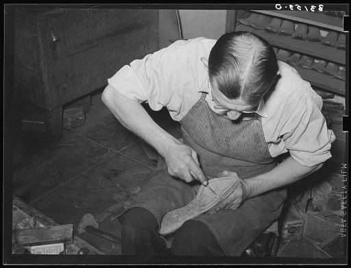 Cowboy bootmaker punching holes in inner sole in Goodyear welt method with awl. Cowboy bootmaking shop, Alpine, Texas