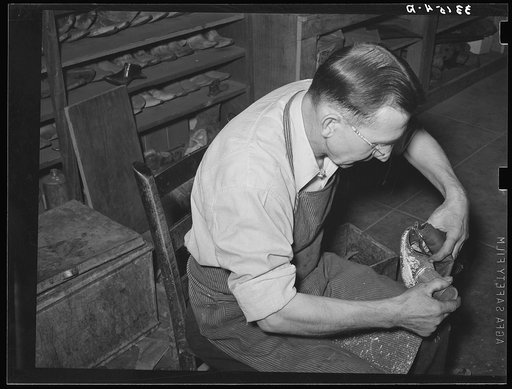 Bootmaker putting tack into upper part of boot before slipping in onto last and sole. Boot shop, Alpine, Texas