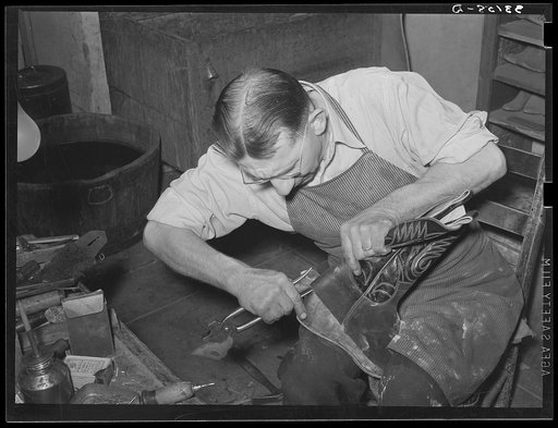 Bootmaker putting lower part of boot around the last for fitting. Bootmaking shop, Alpine, Texas