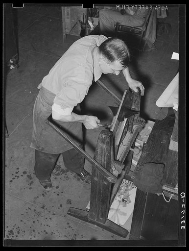 Placing pieces of leather into crimping machine to shape the lowers of the boots. Boot shop, Alpine, Texas