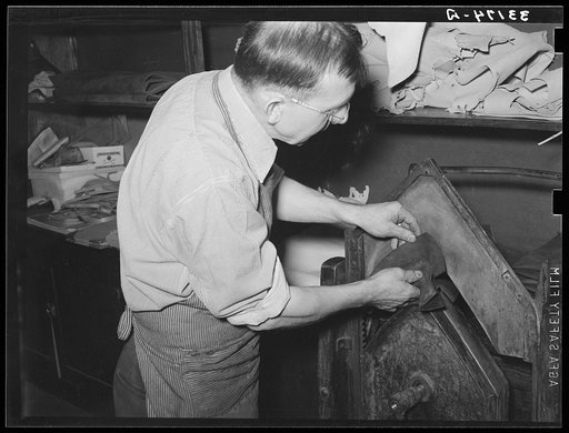 Placing pieces of leather into crimping machine to shape the lowers of the boots. Boot shop, Alpine, Texas