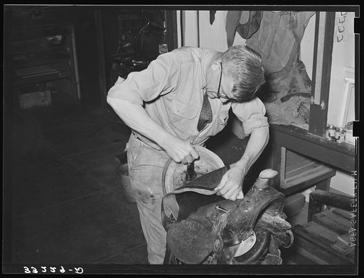 Applying cement for gluing leather of saddle to the base before sewing. Saddle shop, Alpine, Texas