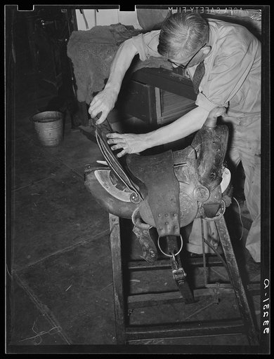 Workman repairing saddle. Alpine, Texas, saddle shop
