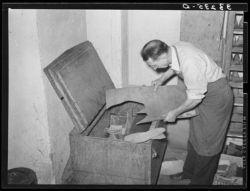 Selecting a piece of leather from the tempering chest. Cowboy boot shop, Alpine, Texas