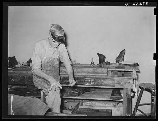 Preparing waxed thread by rolling thread between hand and knee. Boot shop, Alpine, Texas
