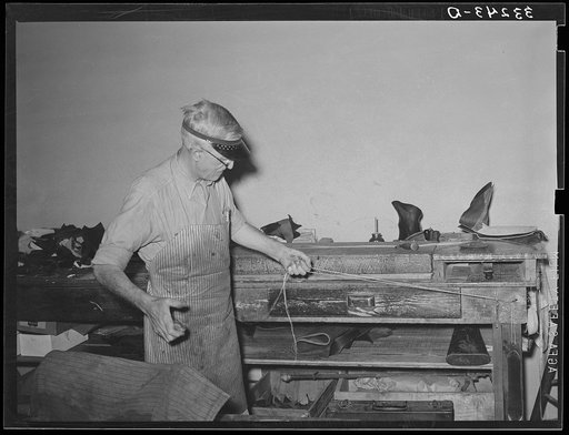 Waxing thread for use in sewing boots. Bootmaking shop, Alpine, Texas