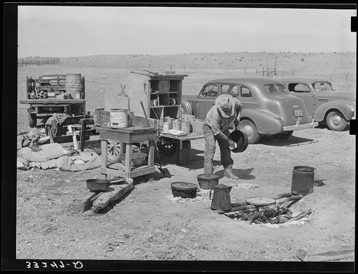 Camp cook at work with chuck wagon in center and truck for carrying bed rolls at left. Cattle ranch near Marfa, Texas