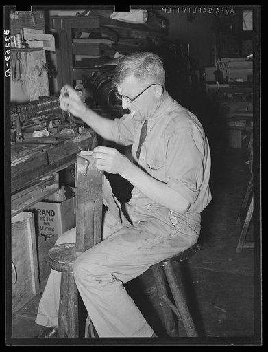 Sewing pieces of leather together on saddle maker's bench. Saddle shop, Alpine, Texas
