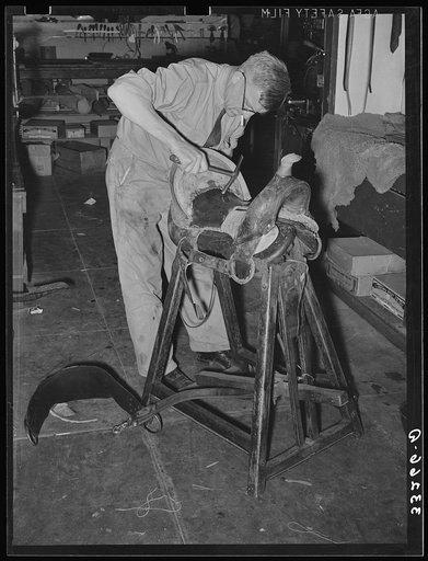 Saddle maker tamping leather in place after cementing it. Saddle shop, Alpine, Texas