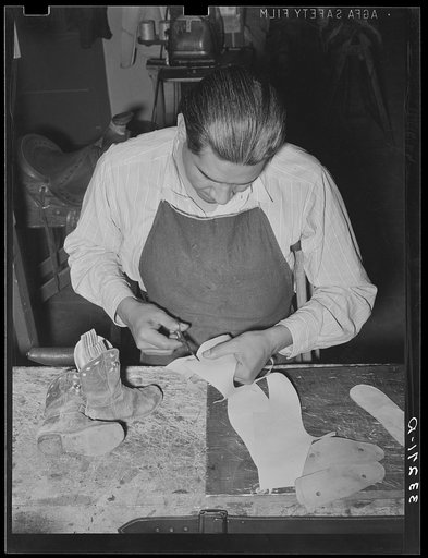 Cutting pieces of leather to repair child's cowboy boots. Saddle shop, Alpine, Texas