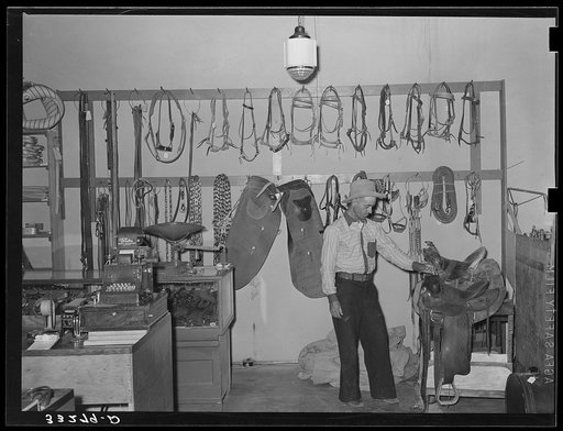 Cowboy examining saddle. Ranch supply store, Alpine, Texas