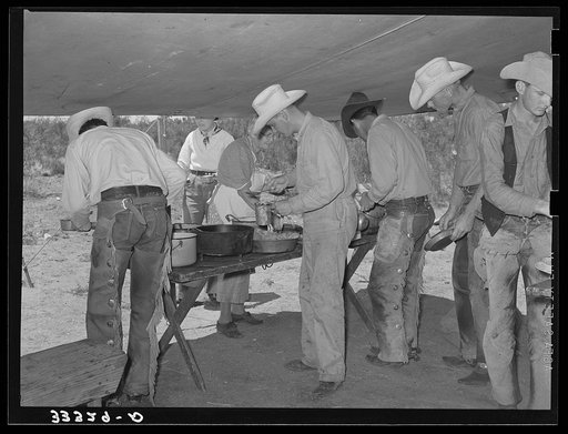 Cowboys of the SMS Ranch serving themselves at dinner at chuck wagon. Ranch near Spur, Texas