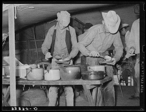 Cowboys of the SMS Ranch serving themselves at dinner at chuck wagon. Ranch near Spur, Texas