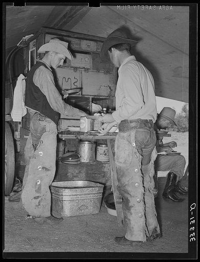 Cowboys of the SMS Ranch serving themselves at dinner at chuck wagon. Ranch near Spur, Texas