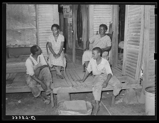 Family of Negro agricultural day laborers sitting on the front proch of their home in Muskogee County, Oklahoma