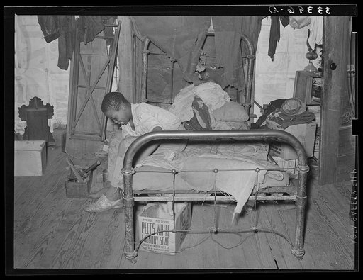 Negro agricultural day laborer putting on his shoes. Muskogee, Muskogee County, Oklahoma