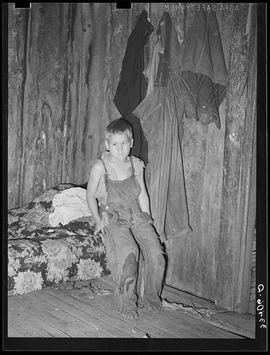 Son of agricultural day laborer in corner of room. The garments hanging on the wall were all the clothes this family of three possessed excepting a wornout coat for the girl. Webbers Falls, Oklahoma