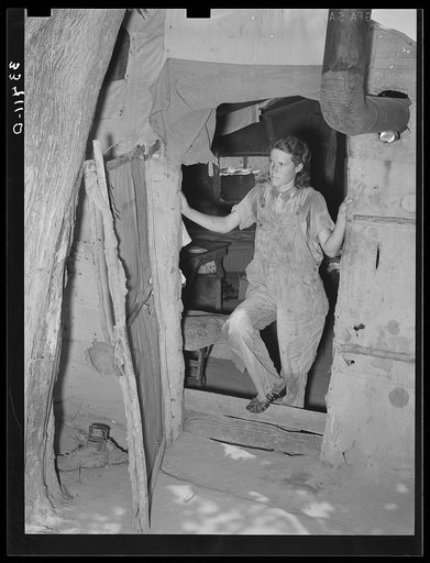 Woman agricultural day laborer standing in the doorway of her tent home.  Near Webbers Falls, Oklahoma. Muskogee County