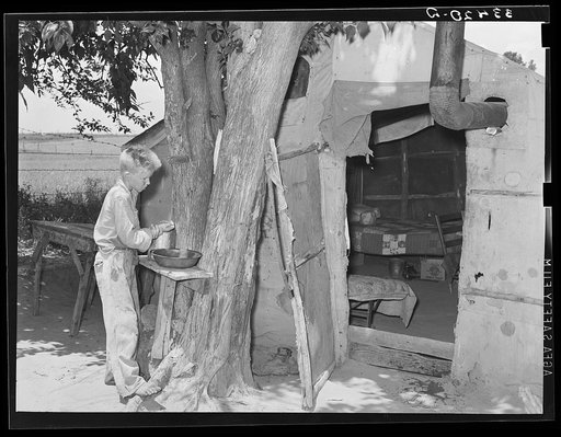 Child agricultural day laborer washing up in front of his tent home near Webbers Falls, Oklahoma. Muskogee County
