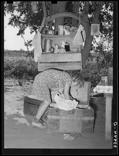 Migrant child packing a trunk at camp home near Muskogee, Oklahoma. Muskogee County