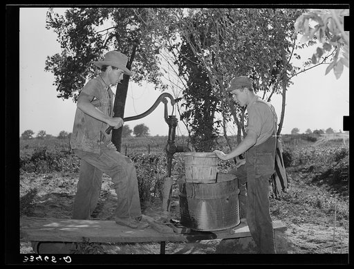Migrant boys pumping water at their shack home near Muskogee. Muskogee County, Oklahoma