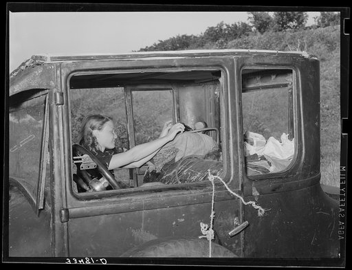 Migrant woman reaching in automobile for supplies while camped near Prague, Oklahoma. Lincoln County, Oklahoma