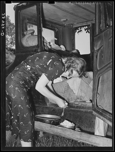 Migrant woman peeling potatoes on running board of car while camped near Prague, Oklahoma. Lincoln County, Oklahoma