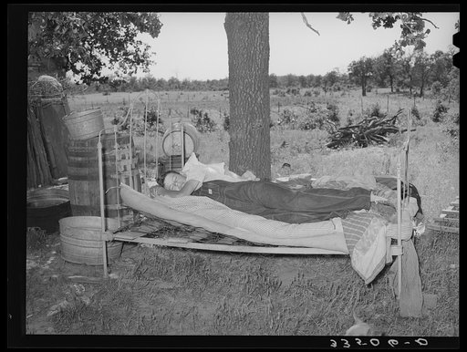 Young migrant agricultural worker on bed outside his home in McIntosh County, Oklahoma