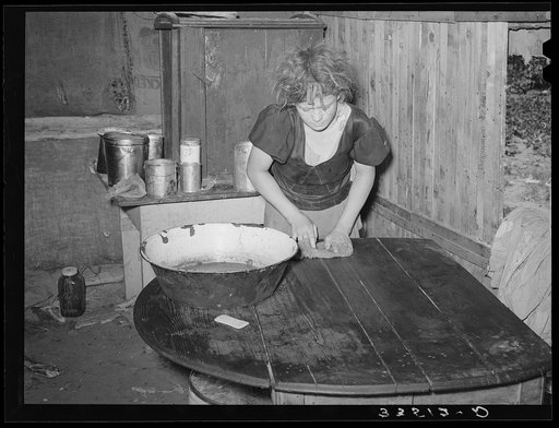 Daughter of agricultural day laborer doing work in the kitchen lean-to of their home. McIntosh County, Oklahoma