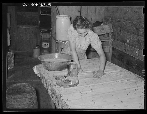 Daughter of agricultural day laborer cleaning up kitchen. Black spots on table cloth are flies. McIntosh County, Oklahoma
