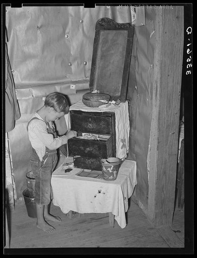 Son of white tenant farmer playing around a dresser in corner of room in his home in McIntosh County, Oklahoma