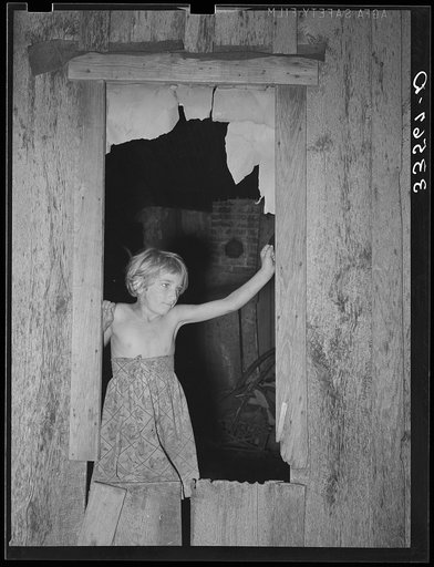 Daugher of day laborer standing in the window of her home in McIntosh County, Oklahoma