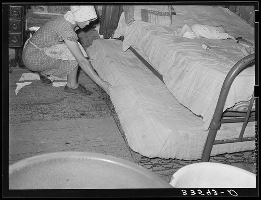 Wife of tenant farmer pulling out trundle bed in her one-room shack home near Sallisaw, Okahoma